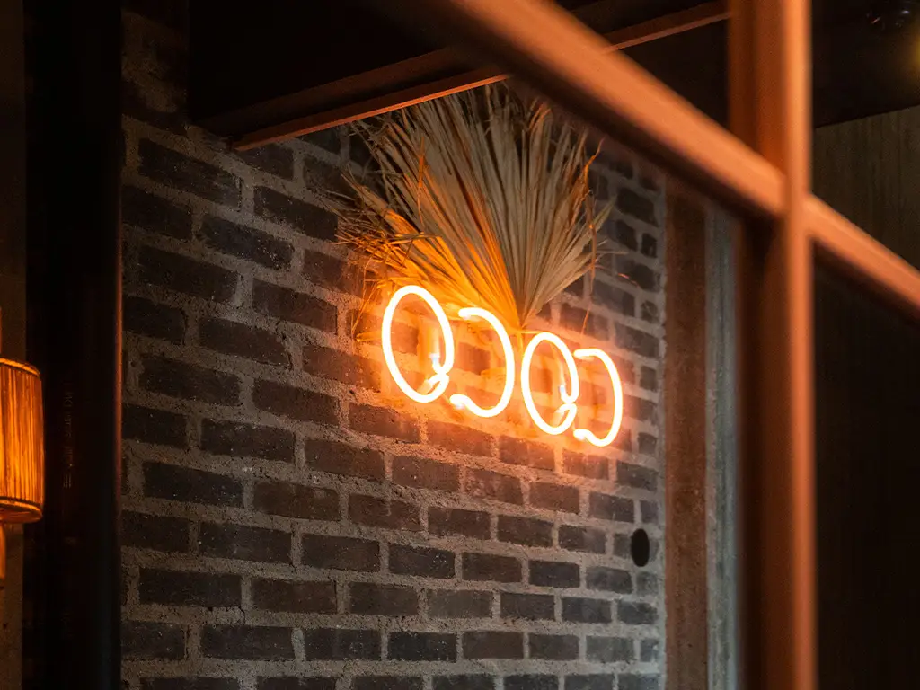 Neonskylt med texten COCO på en tegelvägg på Coco Beach Club