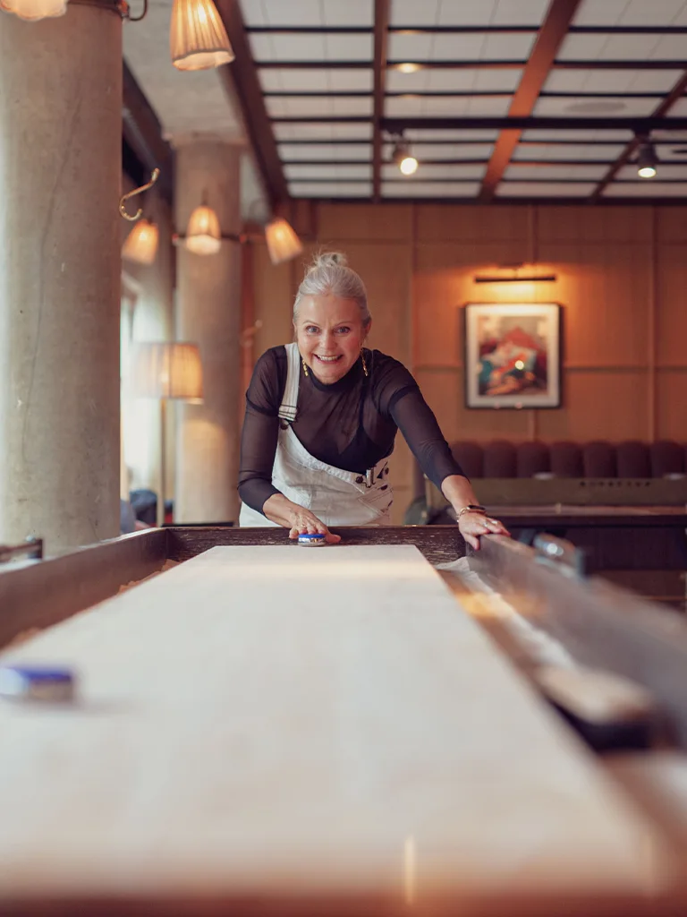 Kvinna spelar shuffleboard i Ellery Playground på Ellery Beach House.