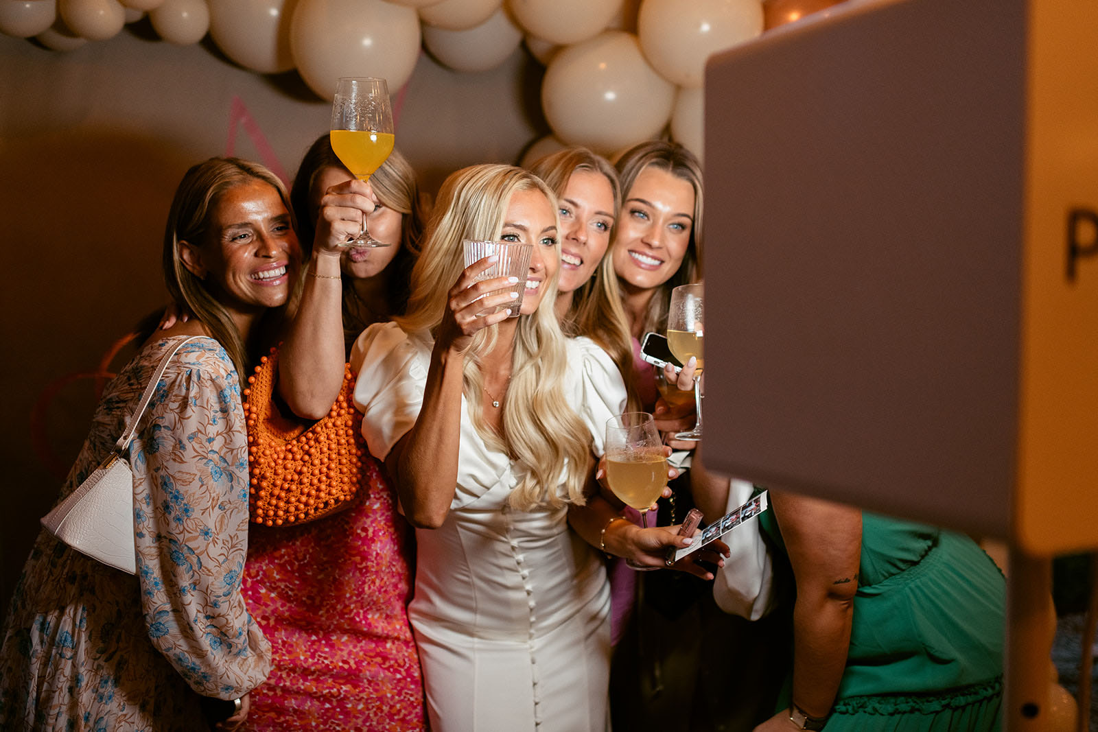 Laughter, Toasts and Moments to Remember Wedding guests raising a toast and taking photos in a photo booth during a wedding celebration at Ellery Beach House
